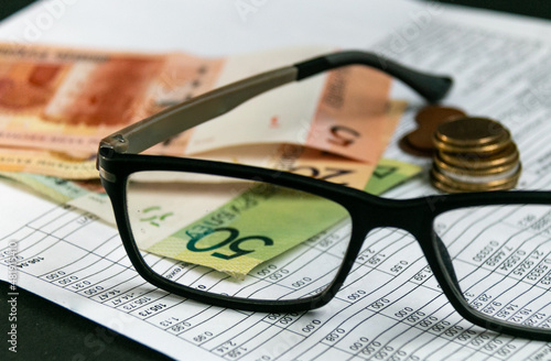 Notice of payment for housing and communal services. Glasses and Belarusian money. The concept of paying bills and increasing prices. Selective focus, narrow focus. Blurred background.