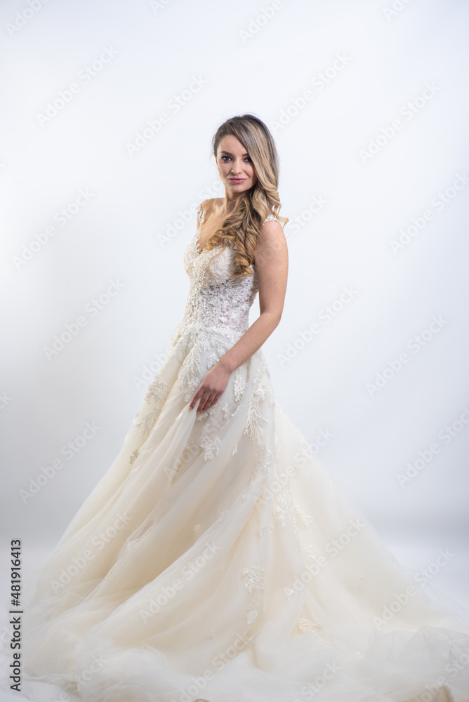 Beautiful attractive bride in wedding dress with long full skirt, white background