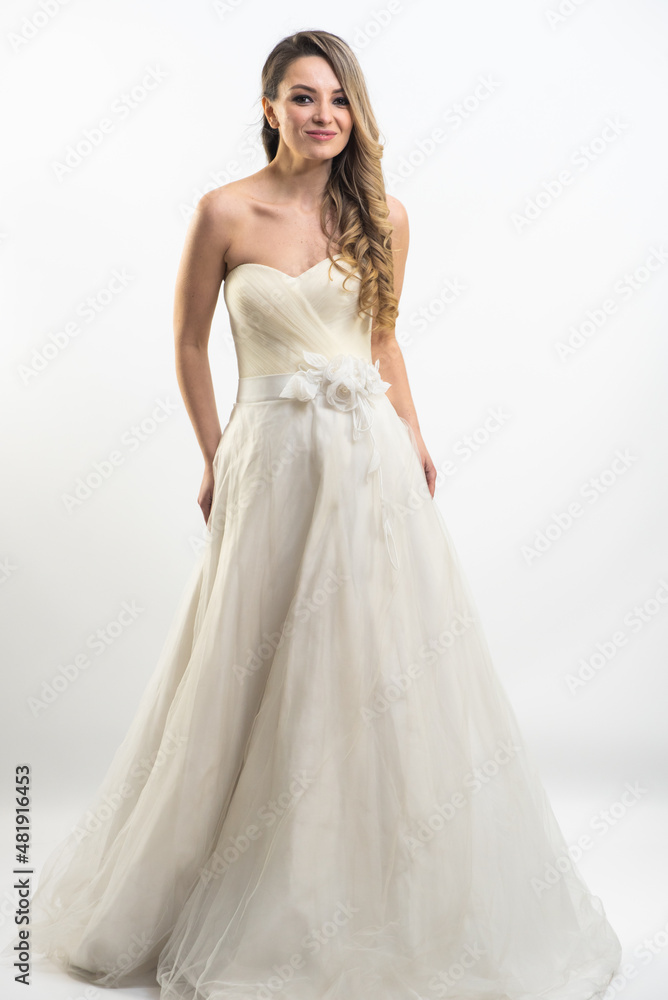 Beautiful attractive bride in wedding dress with long full skirt, white background