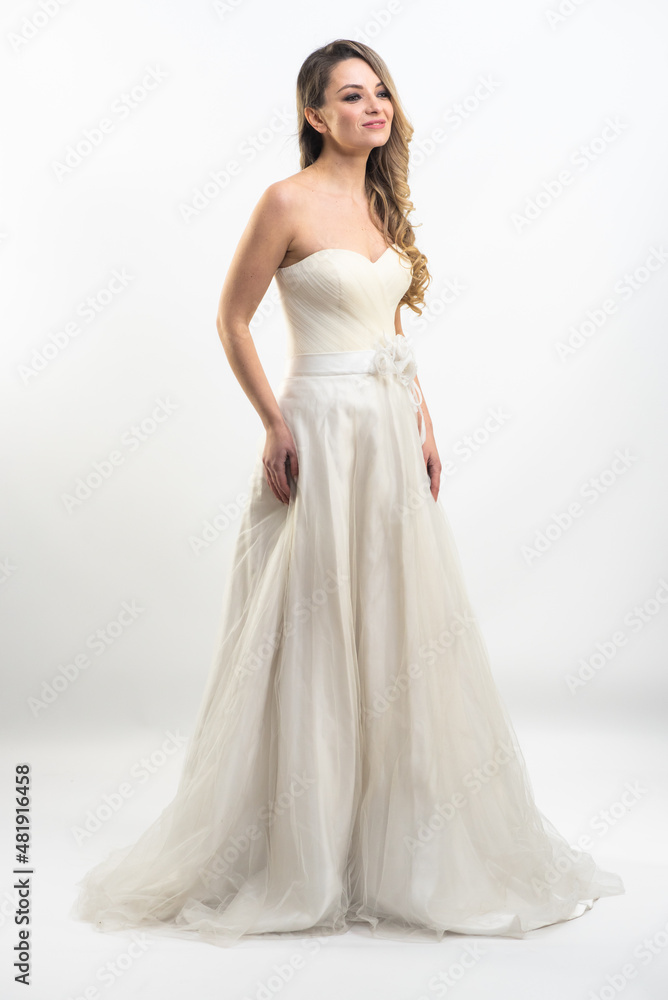 Beautiful attractive bride in wedding dress with long full skirt, white background