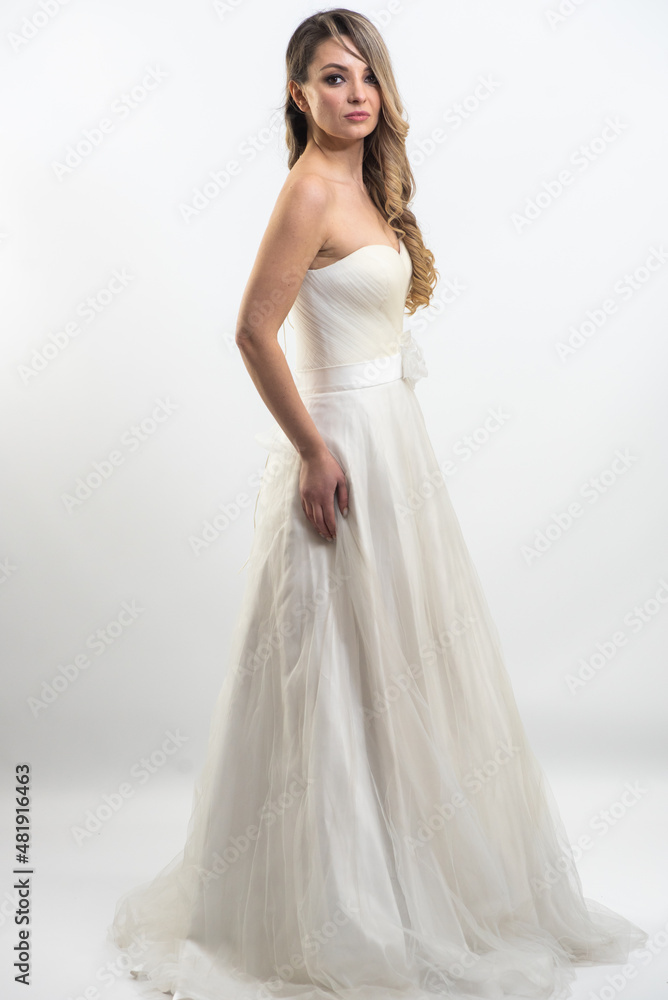 Beautiful bride with fashion hairstyle and make-up wearing wedding dress on white background Beautiful bride with fashion hairstyle and make-up wearing wedding dress on white background