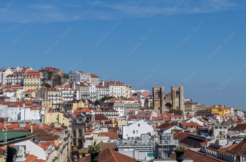 In the background, towers of the Sé de Lisboa Church with Gothic, Baroque and Romanesque architecture between the facades of the houses in the historic center of the city, Portugal.