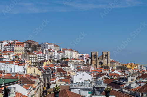 In the background, towers of the Sé de Lisboa Church with Gothic, Baroque and Romanesque architecture between the facades of the houses in the historic center of the city, Portugal.