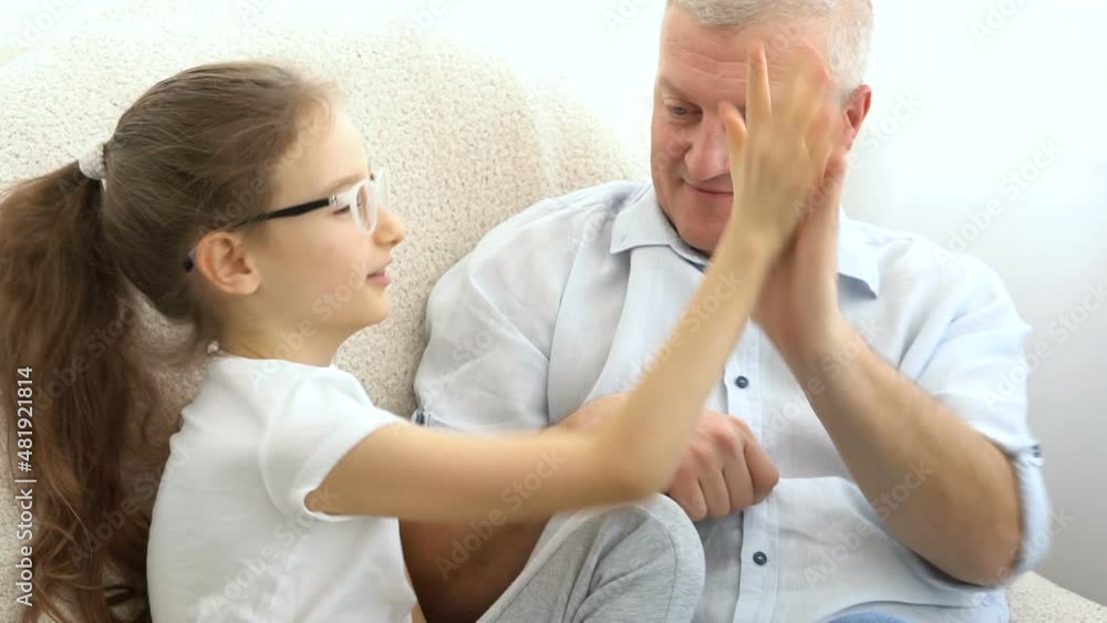 Indoor portrait of grey-haired father and little blonde girl playing with each other at home, father's day concept. Indoor portrait of grey-haired father and little blonde girl playing with each other at home, father's day concept.