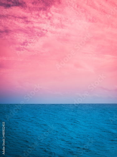 Pink and turquoise-colored seascape. Tranquil vibrant twilight coastal landscape in snow with space for texts and design.