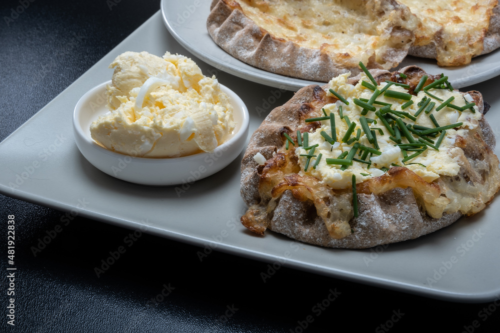 Traditional Finnish foods - Fresh Karelian pies with rice pudding filling and egg butter and chives topping against black background.