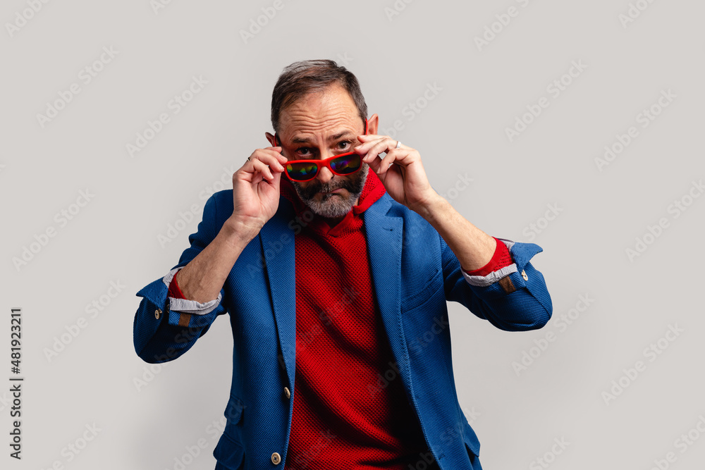 Stylish senior man peeking through sunglasses