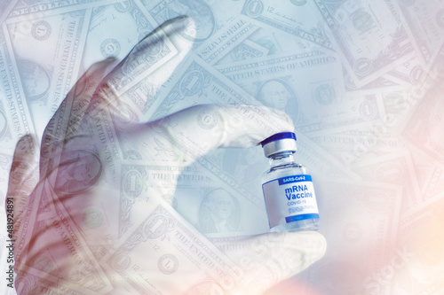 Hand with glove holds a container of covid vaccine, dollar banknotes on the gradient background. Pandemic that has created economic and financial speculation.