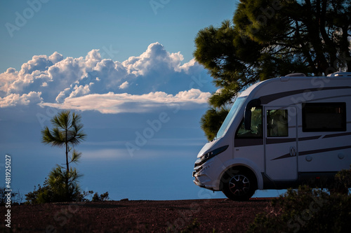Modern elegant motorhome cozy home parked off road with blue sky and clouds in background. Concept of freedom and travel lifestyle for alternative people. Nature park and vehicle