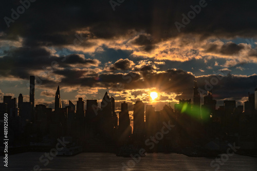 Vivid sunrise over Manhattan skyline with illuminated clouds above the buildings. photo
