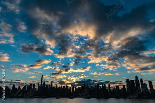 Vivid sunrise over Manhattan skyline with illuminated clouds above the buildings.