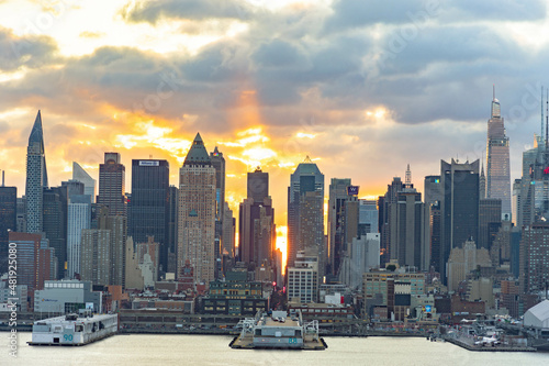 Vivid sunrise over Manhattan skyline with illuminated clouds above the buildings. photo