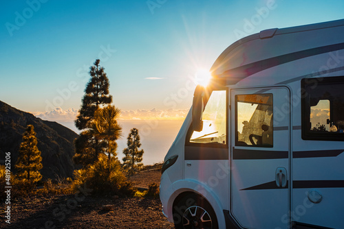 Fotografia Beautiful sunset in background and modern camper van parked in the nature to enjoy freedom and vanlife alternative lifestyle