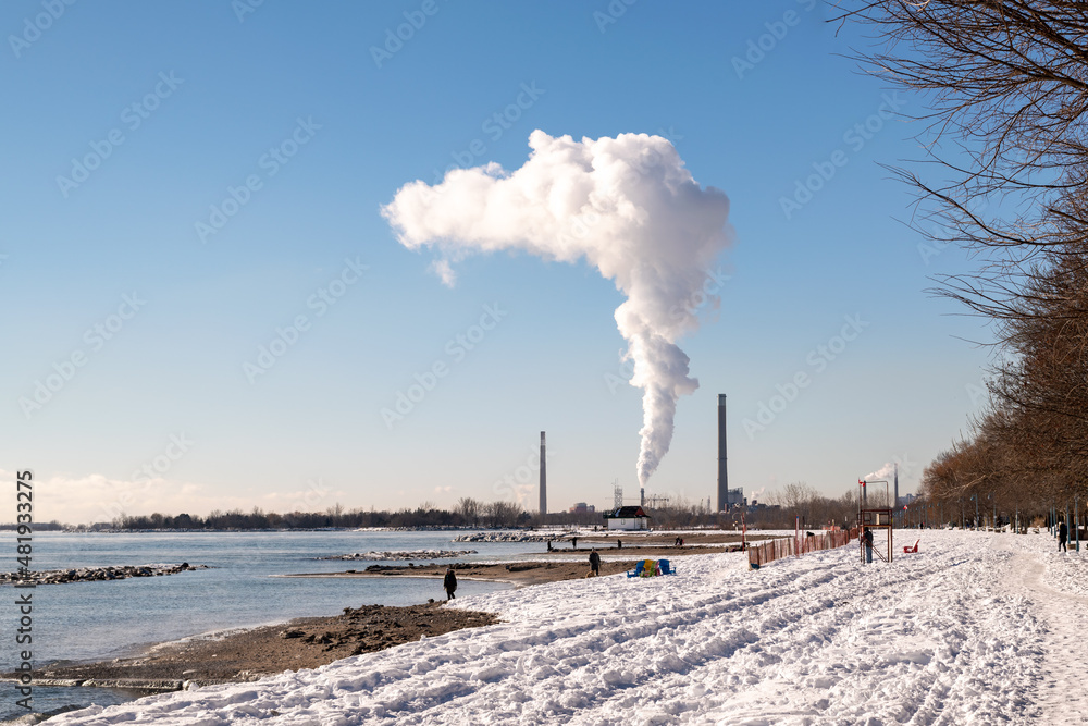 A plume of white  vapour rises from the stacks of a natural gas fired generating station on the shore of Lake Ontario shot on a cold sunny winter's day.  