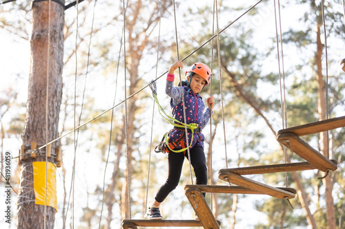 Happy school girl enjoying activity in a climbing adventure park on a autumn day