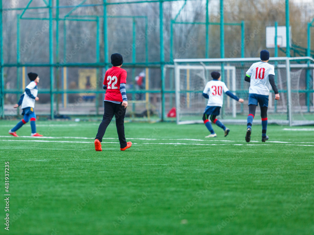 Obraz premium Boy in red white sportswear plays football on field, dribbles ball. Young soccer players teenagers with ball on green grass. 