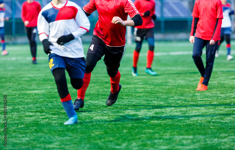 Boy in red white sportswear plays football on field, dribbles ball. Young soccer players teenagers with ball on green grass. Boy in red white sportswear plays football on field, dribbles ball. Young soccer players teenagers with ball on green grass.