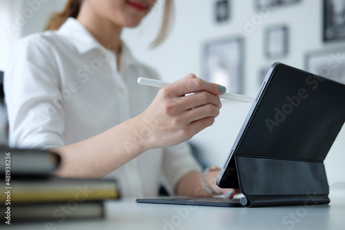 Cropped shot creative woman holding stylus pen writing on screen of digital tablet.