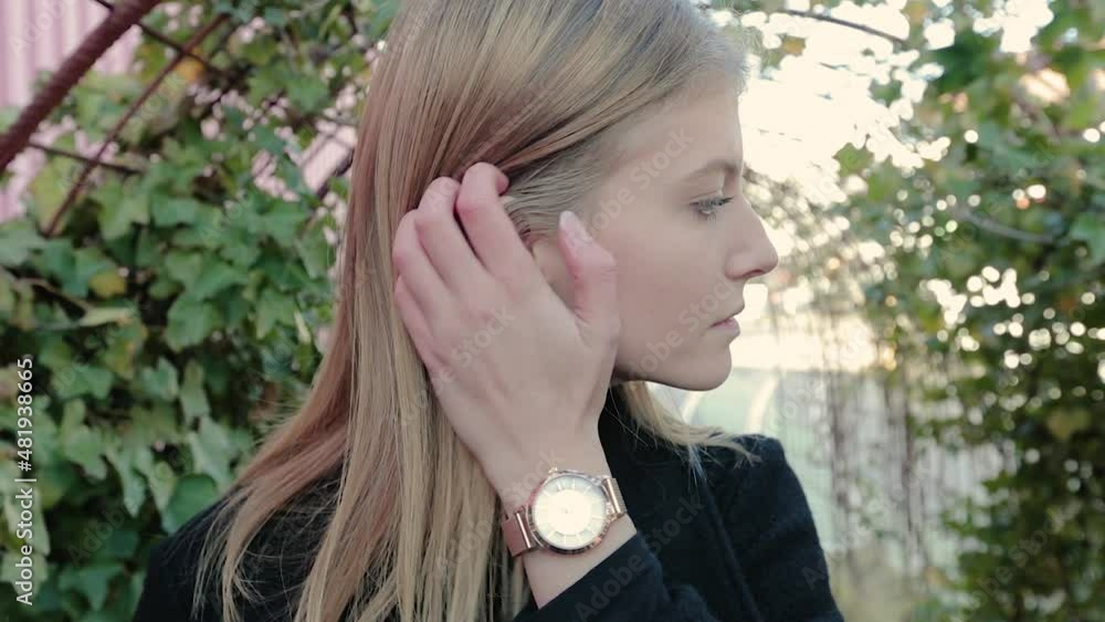 young beautiful woman strokes her hair and looks at the camera. cute woman outside looks at me. Blonde european woman outside young beautiful woman strokes her hair and looks at the camera. cute woman outside looks at me. Blonde european woman outside