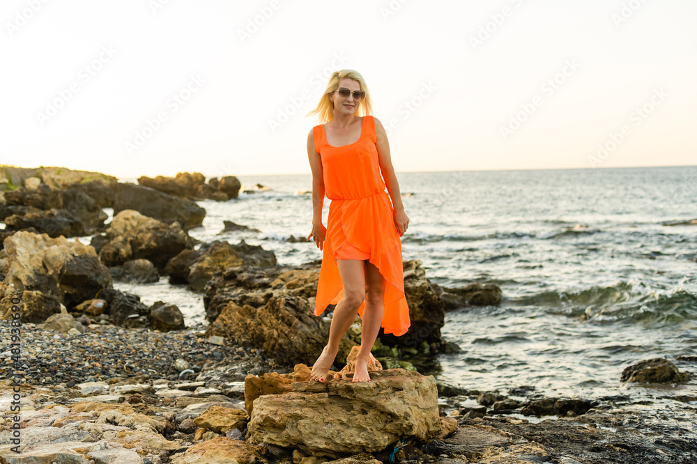 Beautiful woman in dress at the stone sea beach