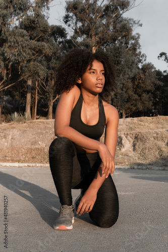 Young brown-skinned woman exercising hard outdoors, sweating in the sun