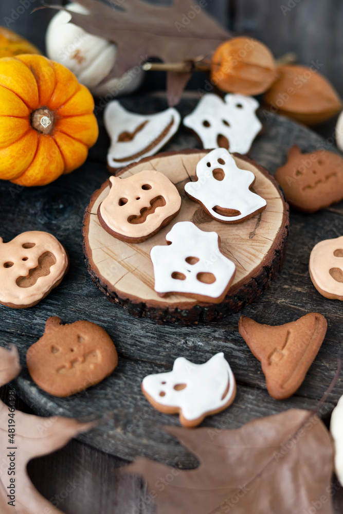 Homemade halloween holiday treats for kids. Gingerbread cookies on wooden board, decorated with pumpkins and autumn leaves. Top view Homemade halloween holiday treats for kids. Gingerbread cookies on wooden board, decorated with pumpkins and autumn leaves. Top view