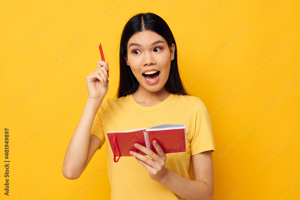 woman writes in a notebook with a pencil yellow background unaltered woman writes in a notebook with a pencil yellow background unaltered