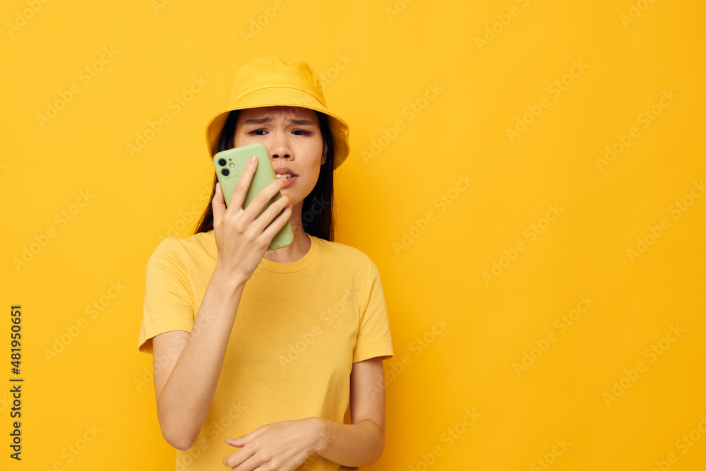 woman in a yellow hat and T-shirt talking on the phone yellow background unaltered woman in a yellow hat and T-shirt talking on the phone yellow background unaltered