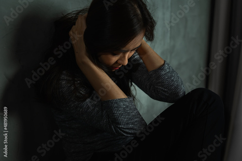Young woman sitting sad, catch head, bow down, depression emotion, looking down in dark room, Portrait of young beautiful woman or female or girl sitting expression depression emotional alone
