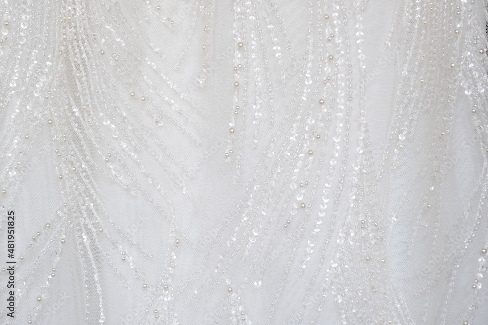 Close up shot at the white luxury gown textile dress with the glitter pattern detail that using with women bride. fashion and clothing background concept. Close up shot at the white luxury gown textile dress with the glitter pattern detail that using with women bride. fashion and clothing background concept.