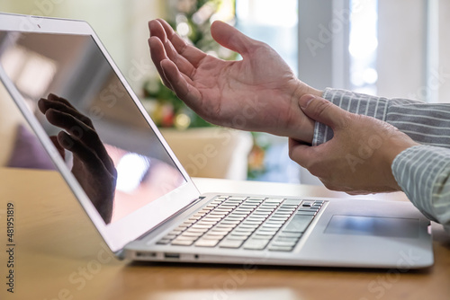 Tableau sur toile Selective focus at the hand of young office worker feeling pain at the wrist from office syndrome, overwork or wrong posture while using computer