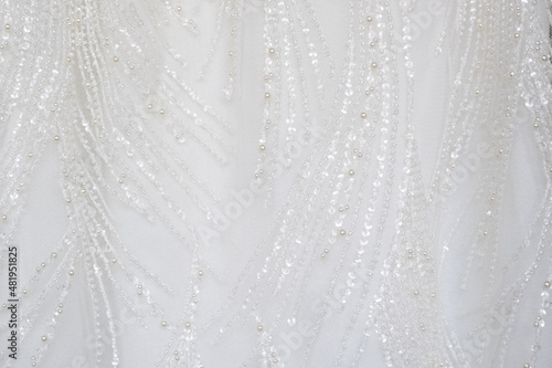Close up shot at the white luxury gown textile dress with the glitter pattern detail that using with women bride. fashion and clothing background concept.