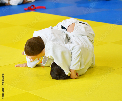 Two Boys judoka in kimono compete on the tatami 