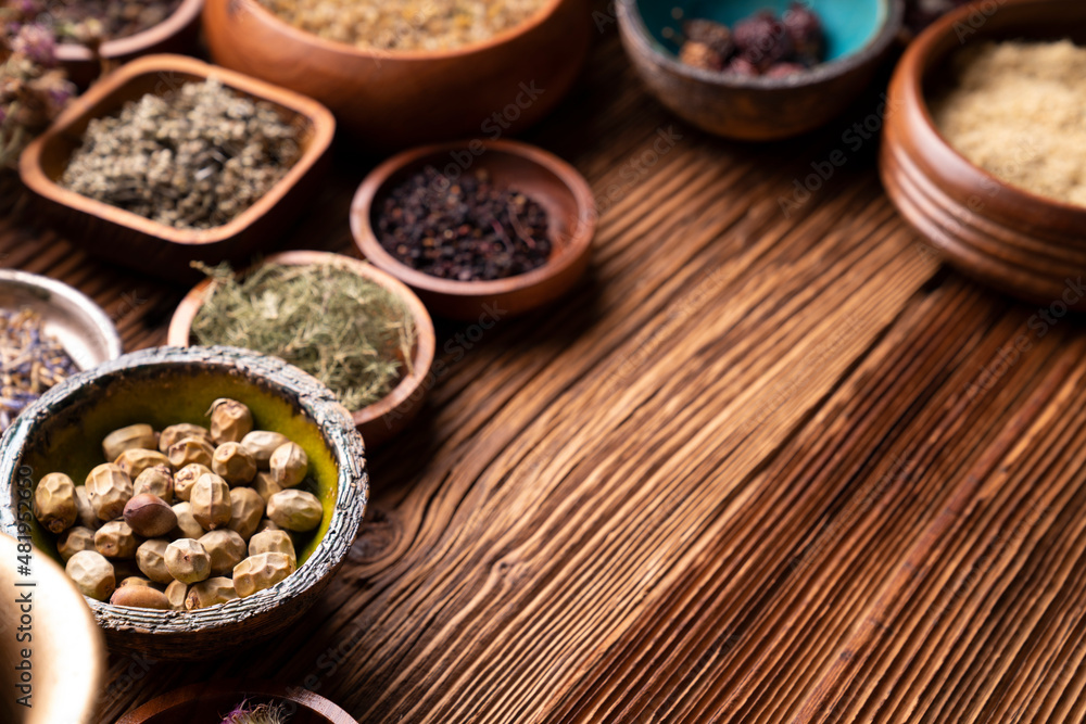 Natural medicine background. Assorted dry herbs in bowls and brass mortar on rustic wooden table. Natural medicine background. Assorted dry herbs in bowls and brass mortar on rustic wooden table.