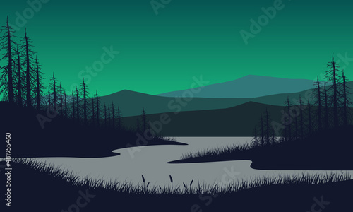 Great mountain view from the riverside at dusk with the silhouettes of dry trees all around