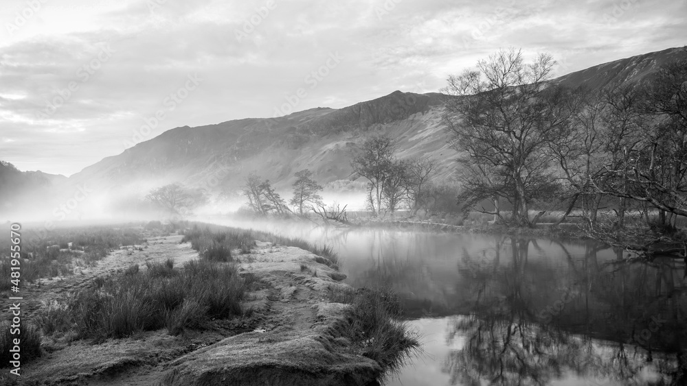 Fototapeta premium Black and white Stunning Autumn landscape sunrise image looking towards Borrowdale Valley from Manesty Park in Lake District with fog rolling across the landscape