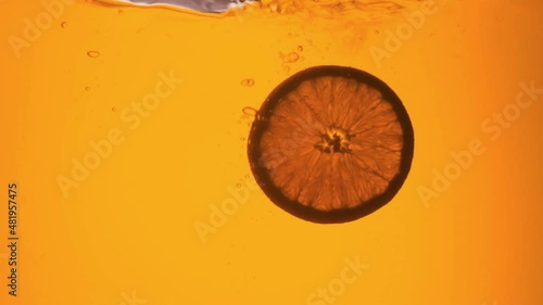 Orange in a glass of juice. Slow motion