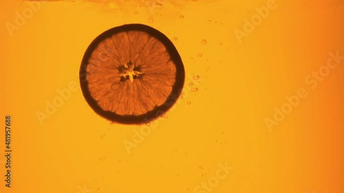 Orange in a glass of juice. Slow motion