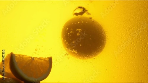 Orange in a glass of juice. Slow motion
