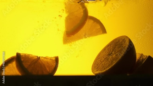 Orange in a glass of juice. Slow motion