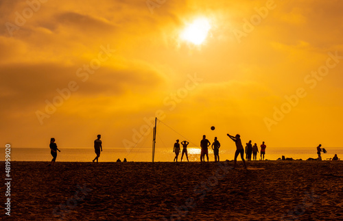 Young people playing volleyball at orange sunset on the beach of San Miguel in the city of Almeria  Andalusia. Spain. Costa del sol in the mediterranean sea