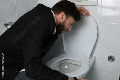 Young businessman vomiting in the toilet 