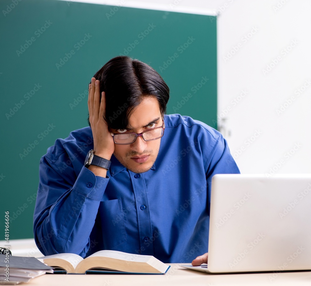 The young male teacher in front of chalkboard The young male teacher in front of chalkboard