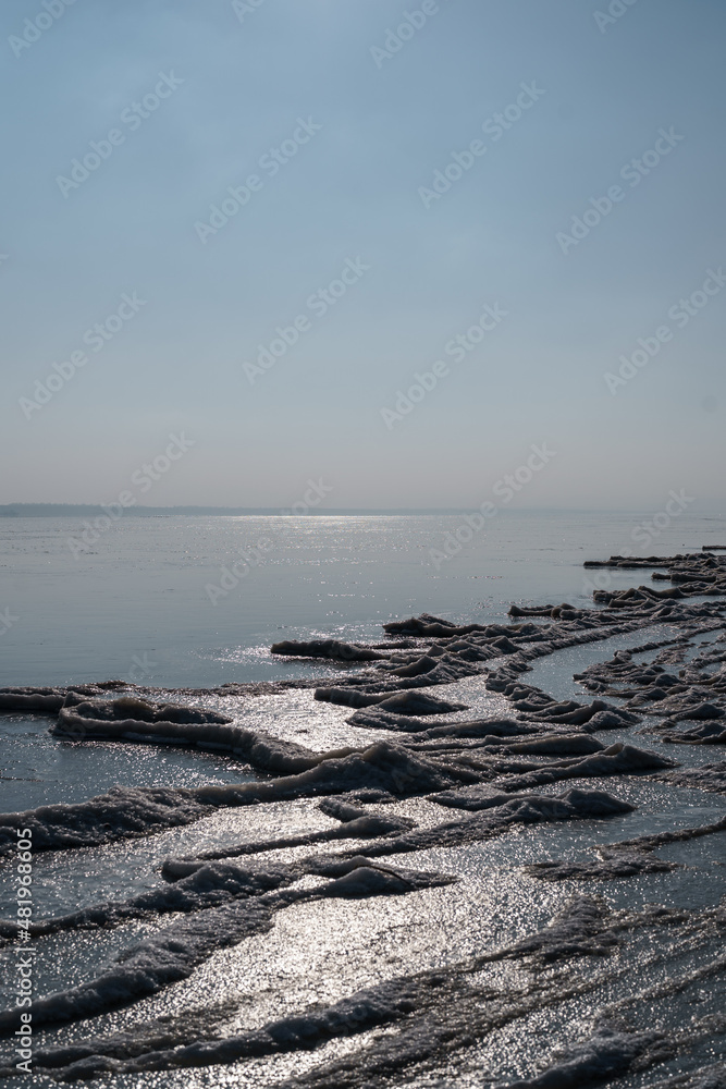 Landscape of a frozen lake, ice, water with blue sky on horizon. Winter cold climate