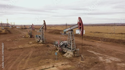 Pump jack in vast oil fields in Russia. Pipelines transporting oil from oil pumps, aerial drone shot