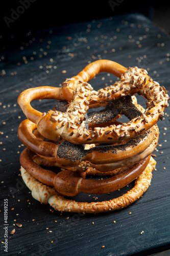 Fresh prepared homemade soft pretzels. Different types of baked bagels with seeds on a black background.