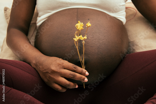 Pregnant woman holding a flower in front of his belly