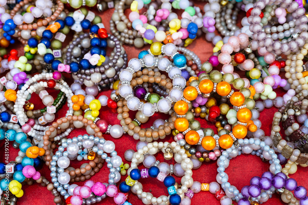 A close-up background of numerous bracelets made of colorful beads.