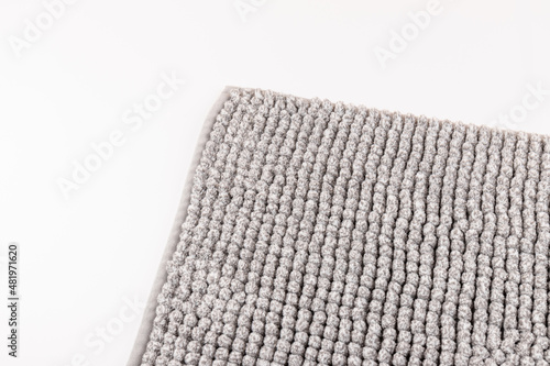 Soft grey bath mat against white background, closeup.Bath Accessories. Top view.
