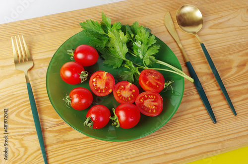 Sliced and whole cherry tomatoes with parsley on a green plate.